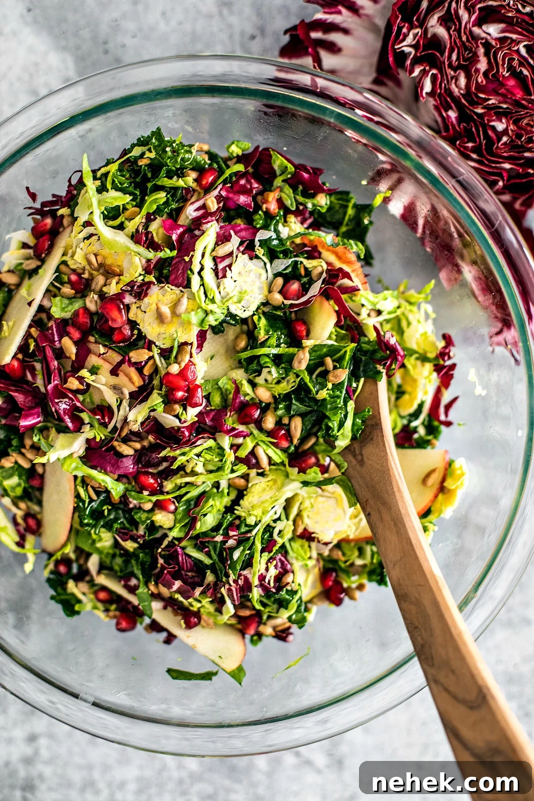 Large serving bowl of winter crunch salad with bright red pomegranate arils.