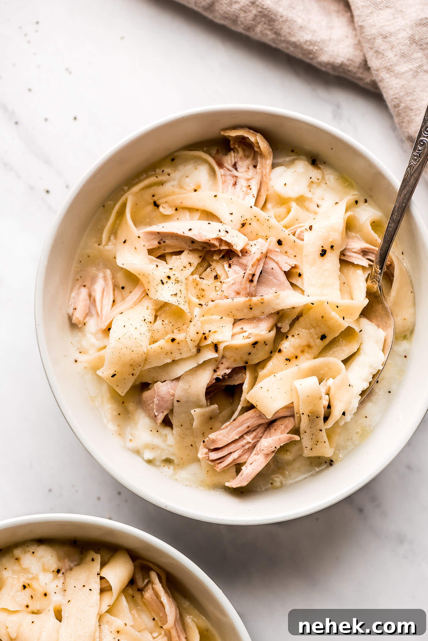 Creamy Chicken and Noodles Served Over Garlic Mashed Potatoes 2 Chicken and Noodles over mashed potatoes in a bowl and a spoon in the side.