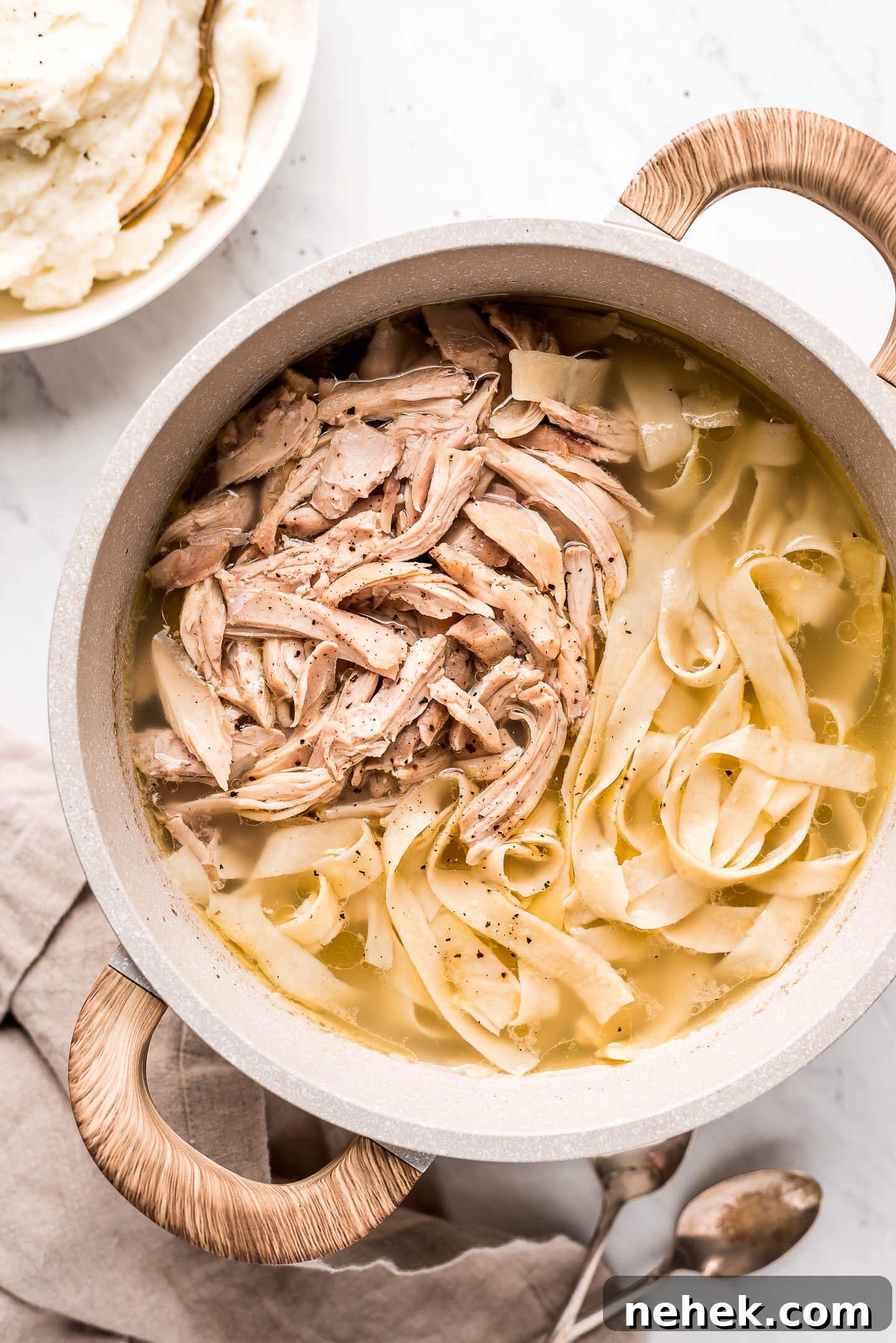Creamy Chicken and Noodles Served Over Garlic Mashed Potatoes 6 A large pot of broth, pasta, and shredded chicken.