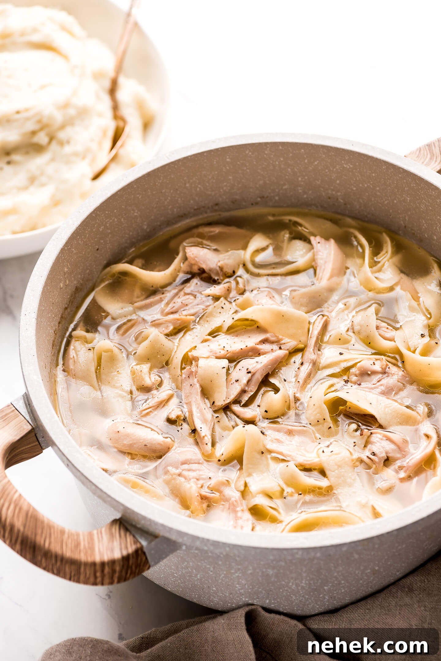 Creamy Chicken and Noodles Served Over Garlic Mashed Potatoes 8 Chicken and Noodles in a pot, sprinkled with black pepper.