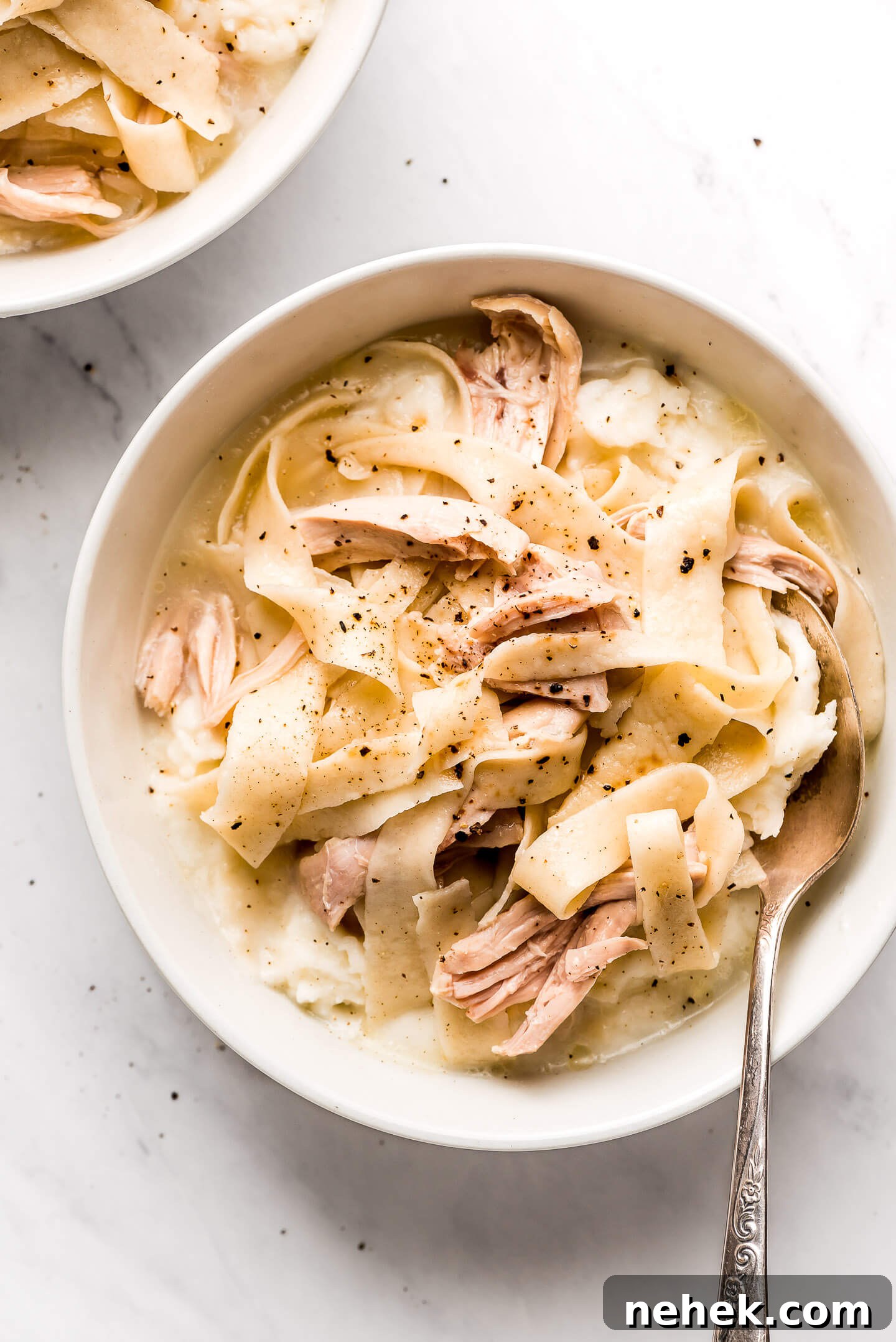Creamy Chicken and Noodles Served Over Garlic Mashed Potatoes 9 A bowl of Amish Chicken and Noodles over mashed potatoes.