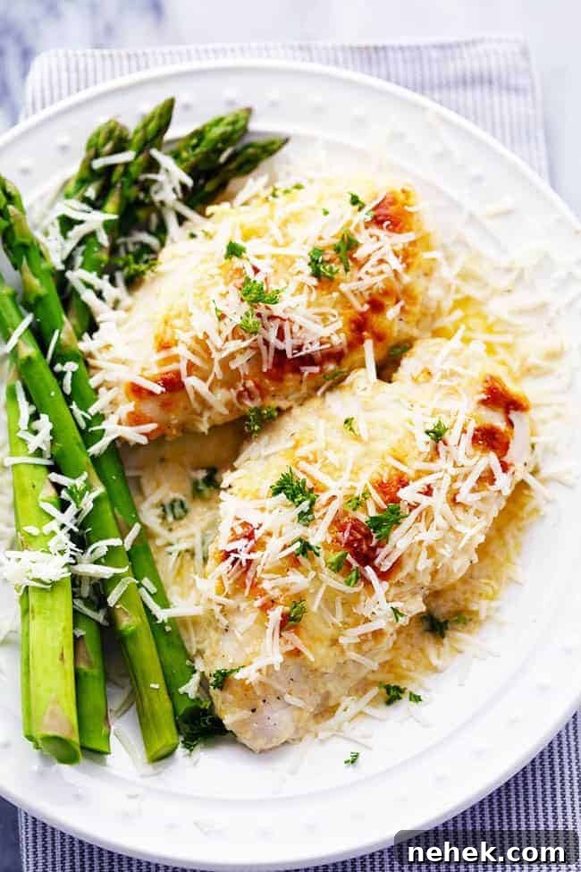 Creamy baked asiago chicken and baked asparagus on a white plate. 