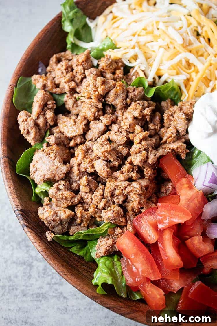 overhead view of turkey taco salad with ground turkey, cheese, chopped tomatoes and sour cream all on a bed of lettuce