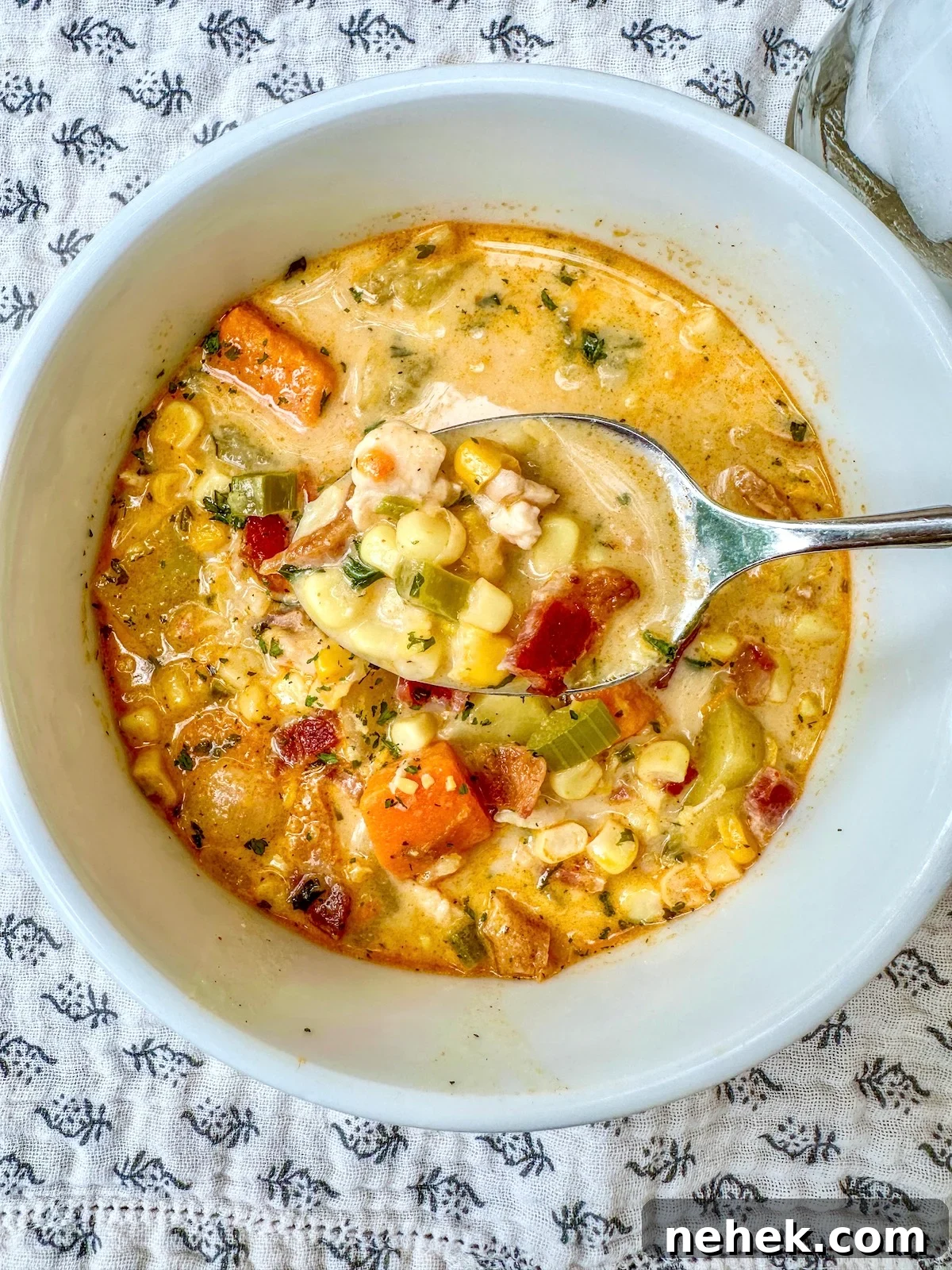 Creamy Corn and Potato Soup Recipe — Comforting Weeknight Soup 2 Creamy corn and potato soup in a bowl with a spoon.