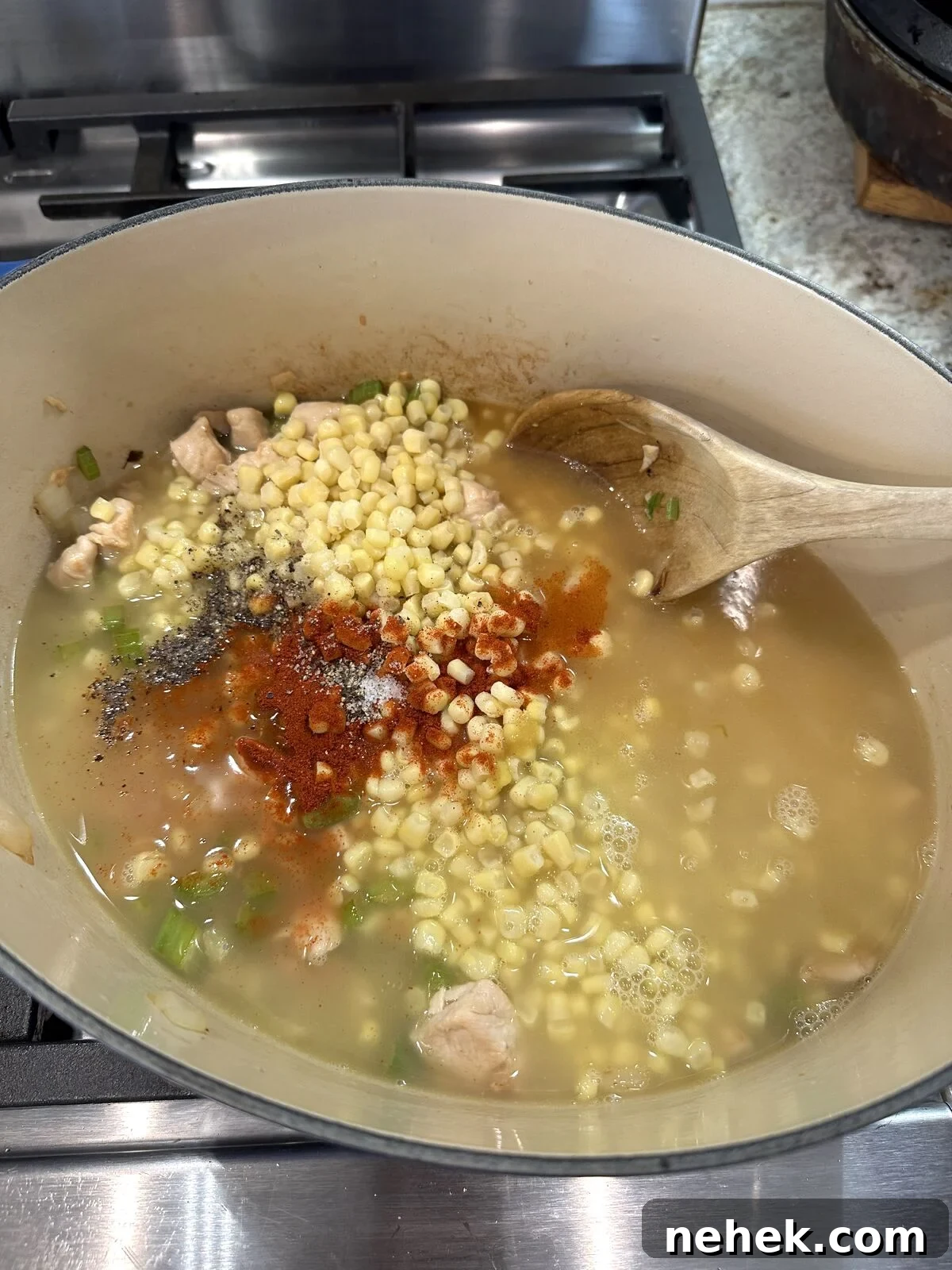 Creamy Corn and Potato Soup Recipe — Comforting Weeknight Soup 7 Corn in liquid ingredients and spices in a pan.