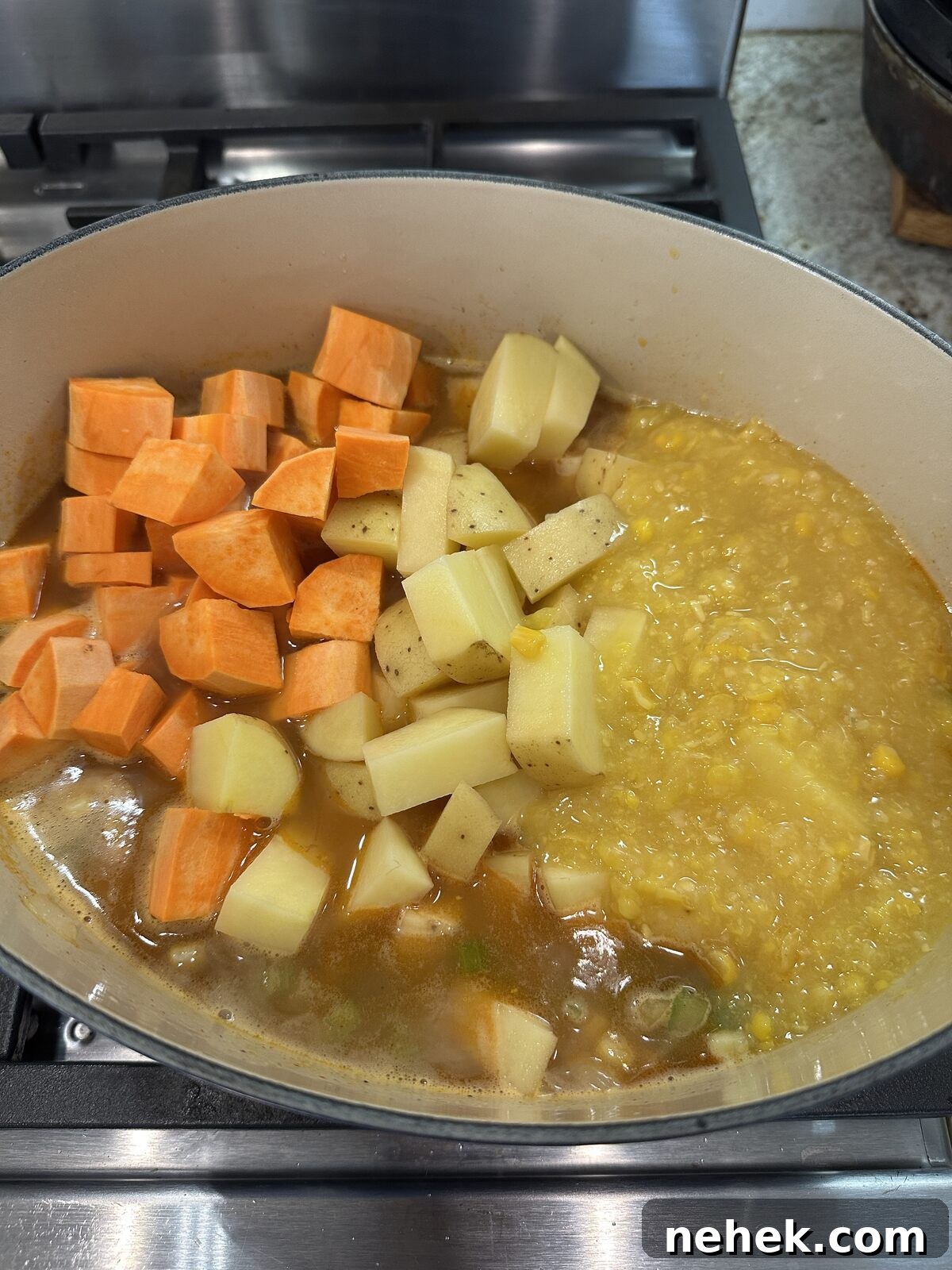 Creamy Corn and Potato Soup Recipe — Comforting Weeknight Soup 8 Potatoes and creamed corn with corn soup ingredients in a dutch oven on the stove.