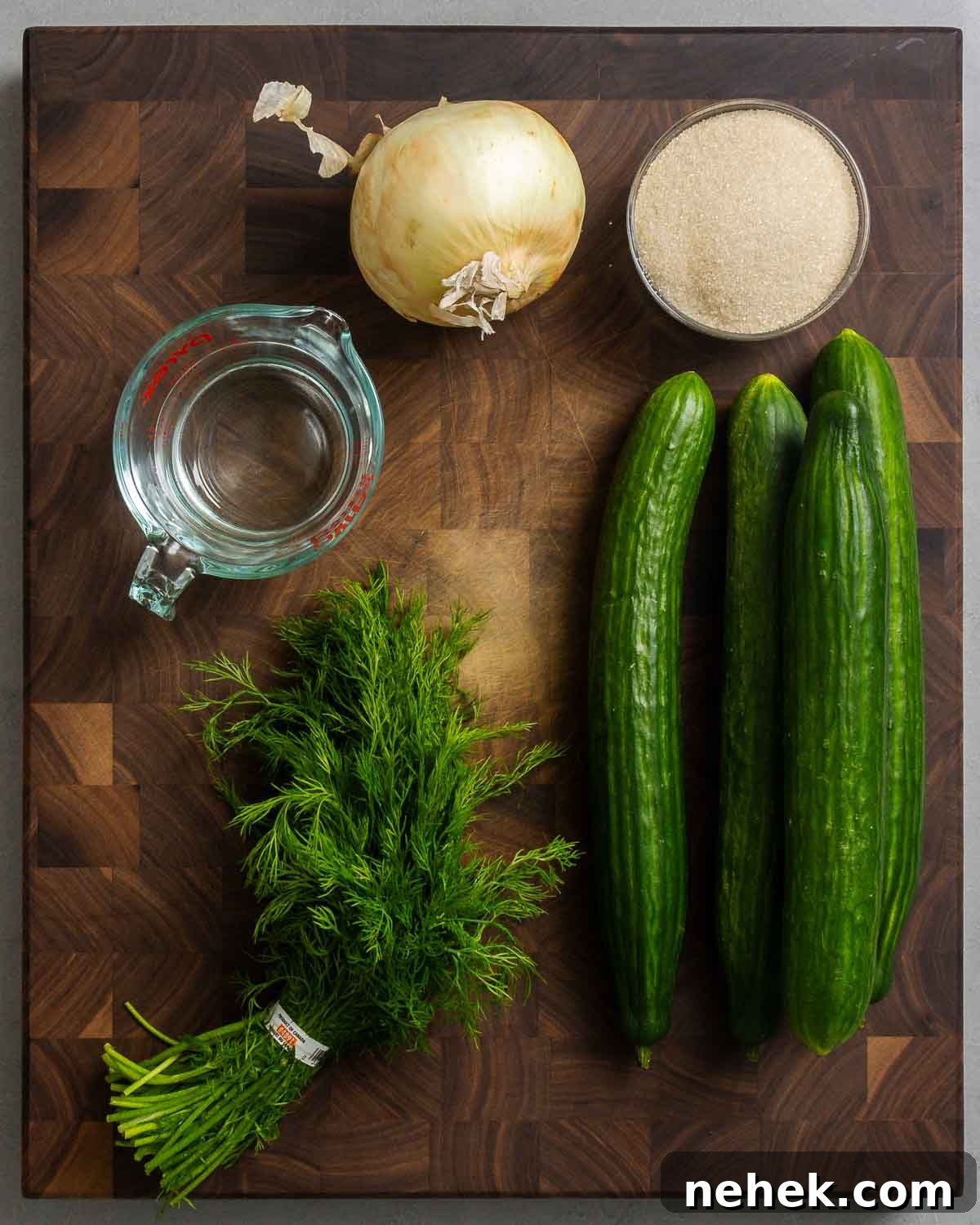 Refreshing Cucumber Salad Recipe with Herbs and Vinegar 3 Ingredients shown: onion, sugar, white vinegar, dill, and cucumbers.