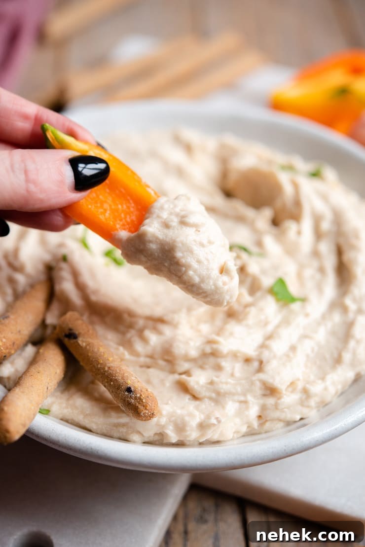 Dipping bell peppers into white bean dip A close up of dipping bell peppers into a white bean dip