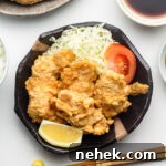 chicken tempura with cabbage, tomatoes and lemon on a black plate