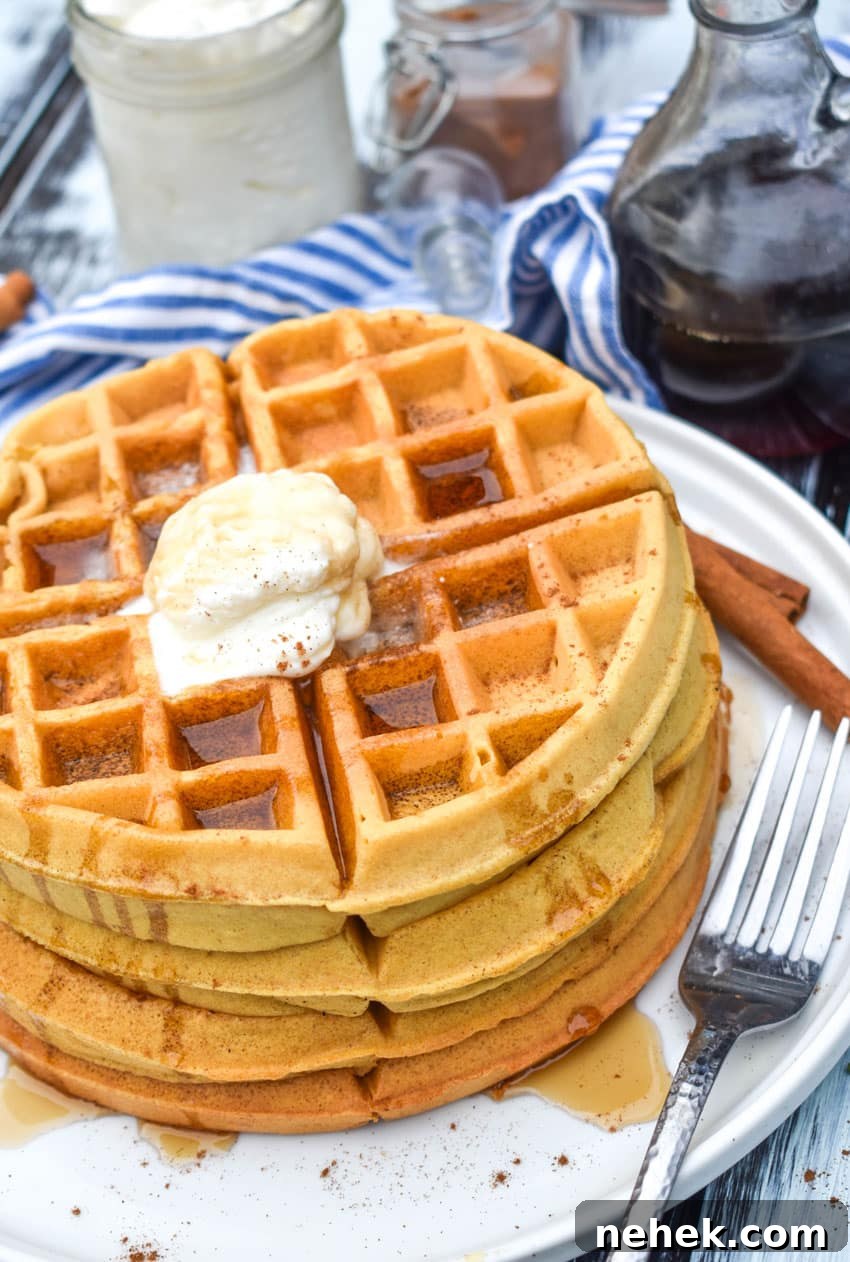 a stack of syrup covered pumpkin spice waffles on a white plate