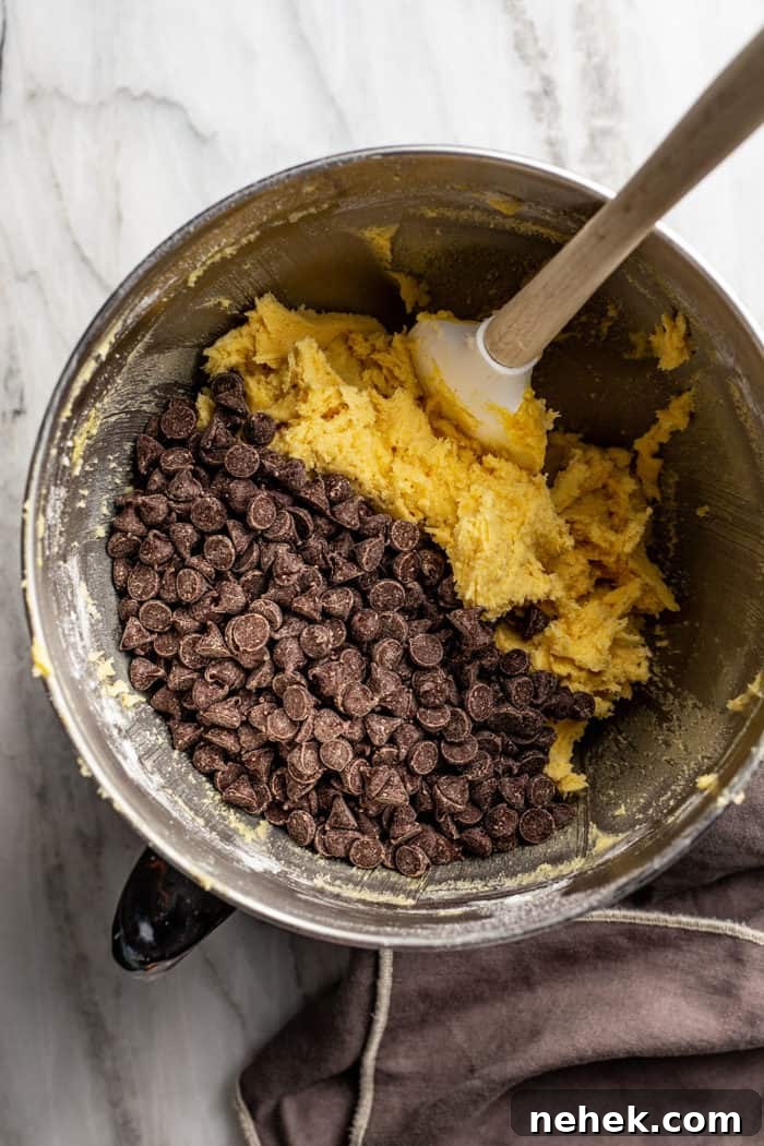 Chocolate Chip Pudding Cookies Recipe — Soft, Chewy Treats 6 Spatula folding chocolate chips into pudding cookie dough