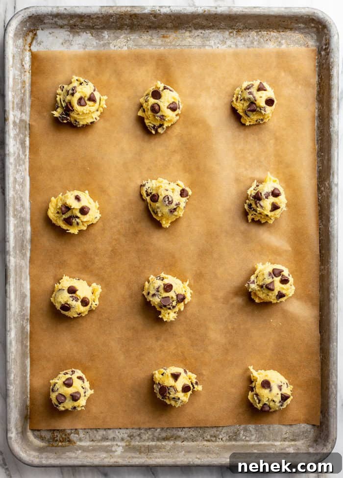 Chocolate Chip Pudding Cookies Recipe — Soft, Chewy Treats 8 Portioned balls of chocolate chip pudding cookie dough on a parchment-lined baking sheet, ready to bake