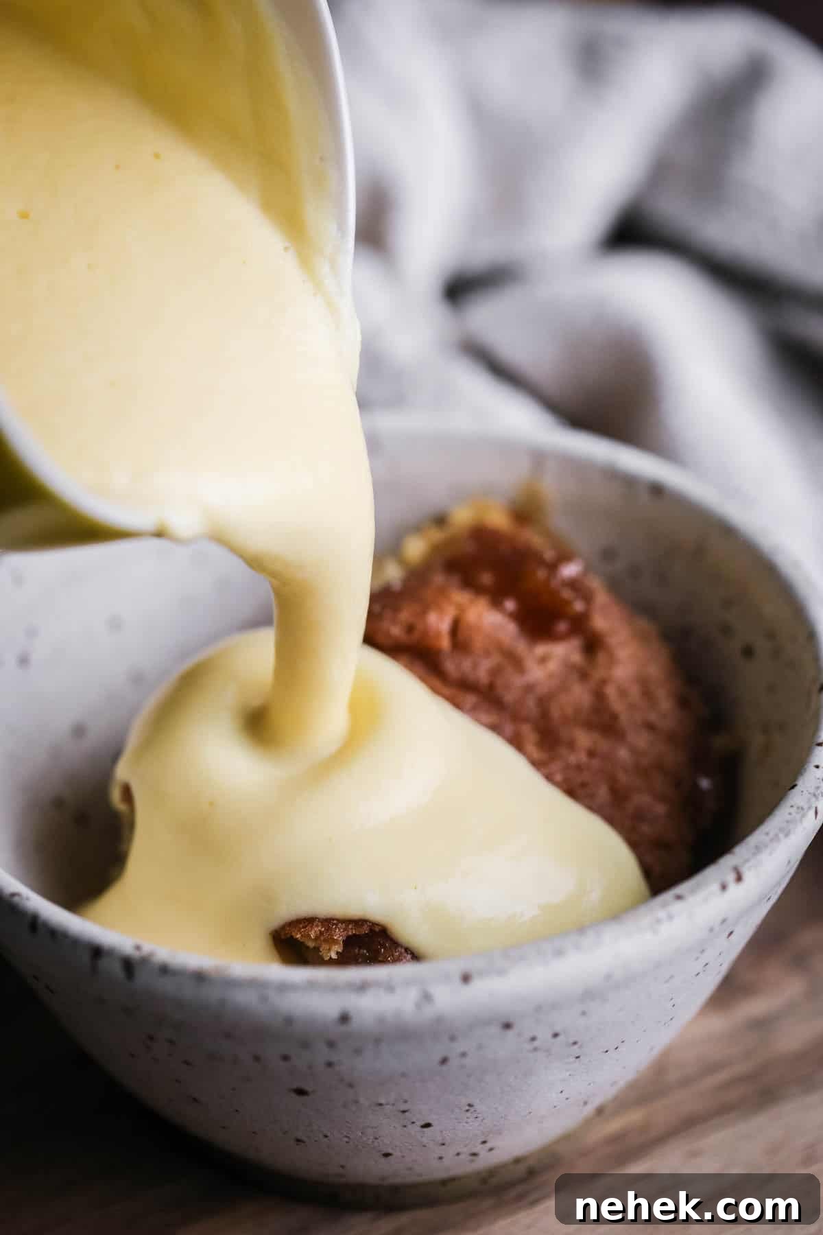 Lemon custard pouring over lemon sponge pudding in a bowl.