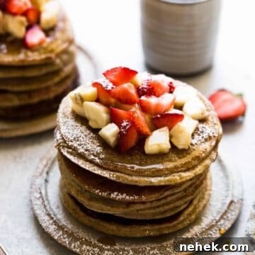 banana oatmeal pancakes on a plate with strawberries and bananas on top