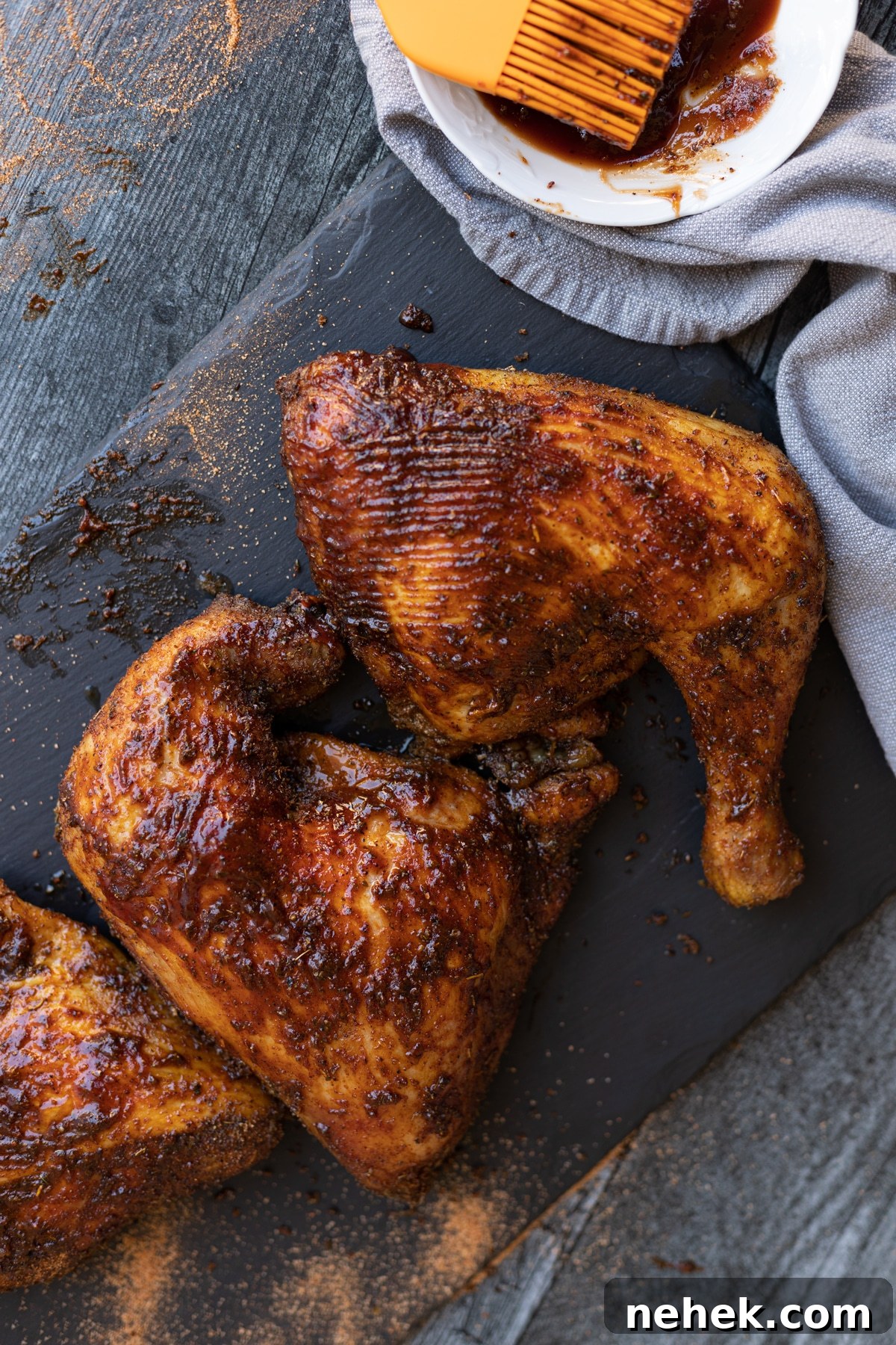 How to Smoke Chicken Leg Quarters for Juicy, Flavorful Results 12 Smoked chicken quarters on a slate plate topped with BBQ sauce.
