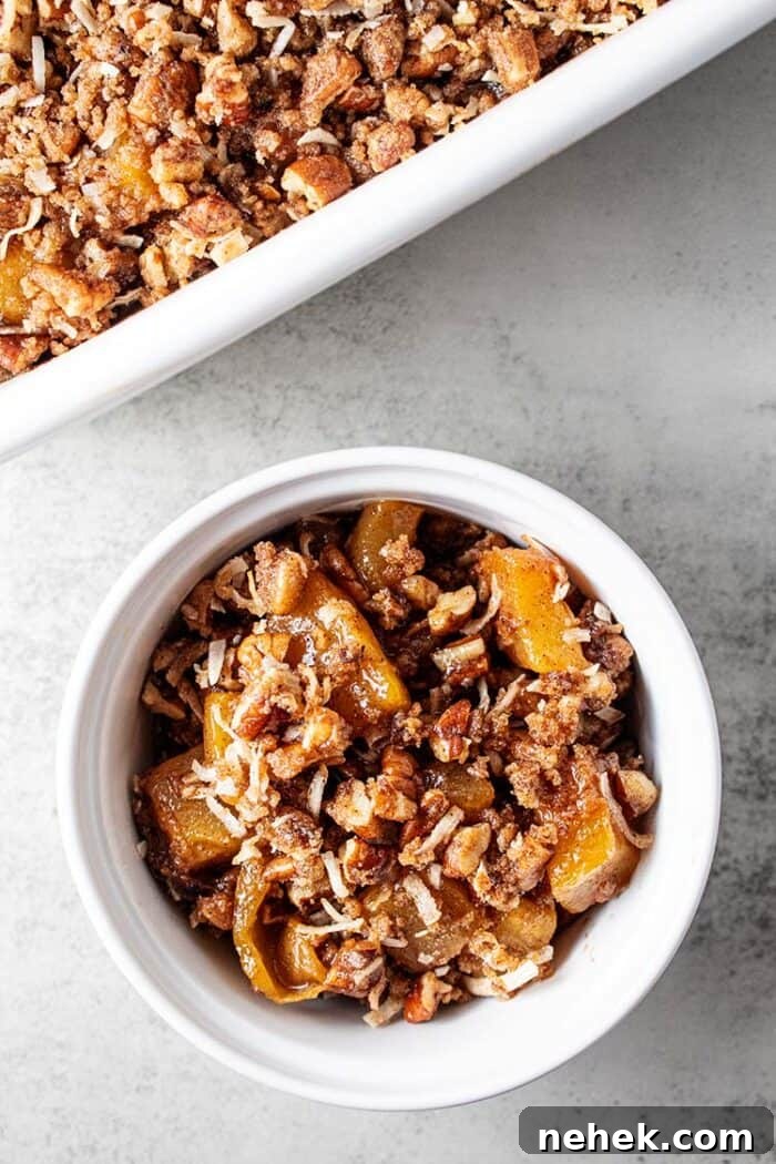 overhead view of white serving bowl with low carb gluten free keto apple crisp in it and casserole dish with apple crisp in it at the top of the image
