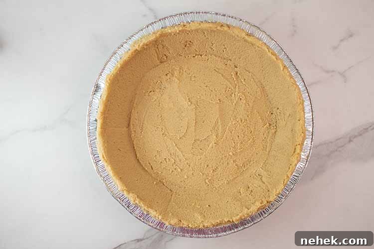 overhead view of keto pie crust in a aluminum foil pie tin ready to be baked