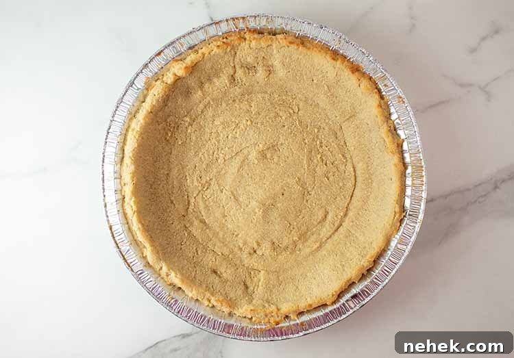 overhead view of keto pie crust in a aluminum foil pie tin out of the oven and cooling off