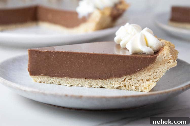 sideview of a slice of keto chocolate pudding pie on a serving plate topped with whipped cream