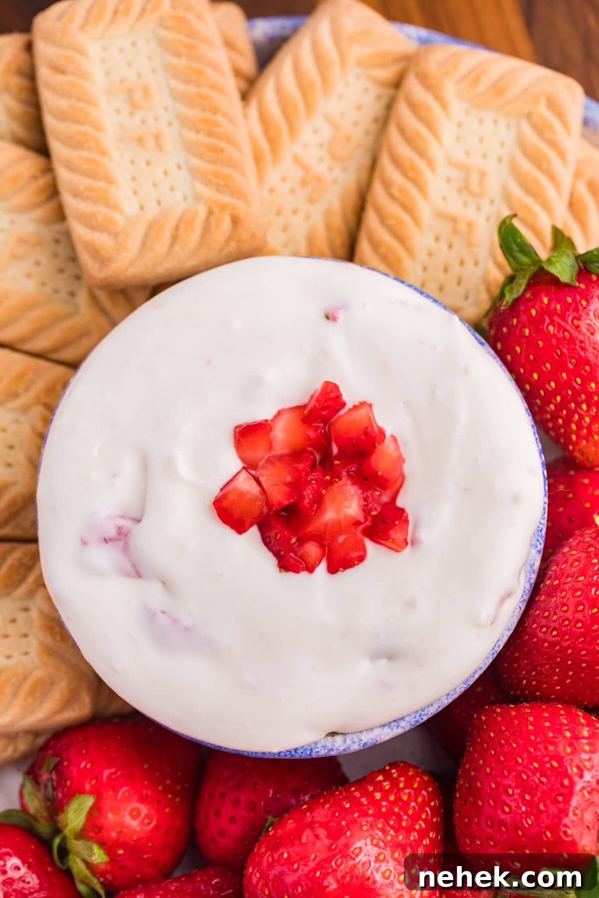 Creamy Strawberry Cheesecake Dip Recipe for Parties 6 The dip surrounded by cookies and strawberries.