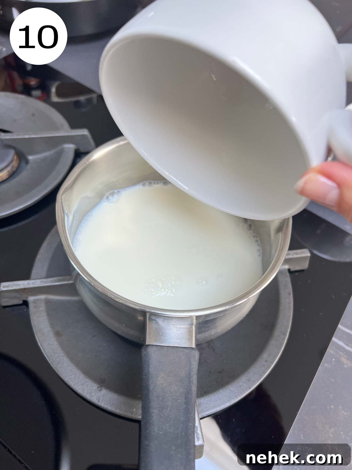 Ultimate Moist Chocolate Cake Recipe for Rich, Decadent Results 13 Preparing the milk sauce - milk being added from a white ceramic mug into a stainless steel pot.