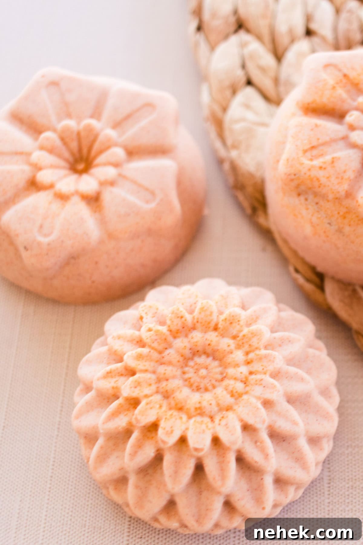 Homemade Turmeric Soap Recipe for Glowing Skin 2 Flower-shaped orange soap bars on a wicker placemat.