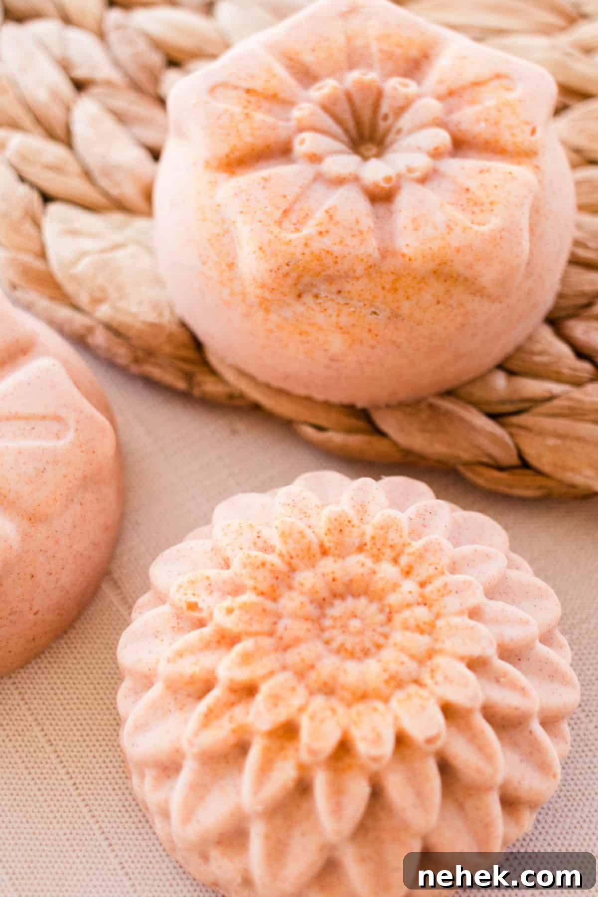 Homemade Turmeric Soap Recipe for Glowing Skin 14 Flower-shaped orange soap bars on a wicker placemat.