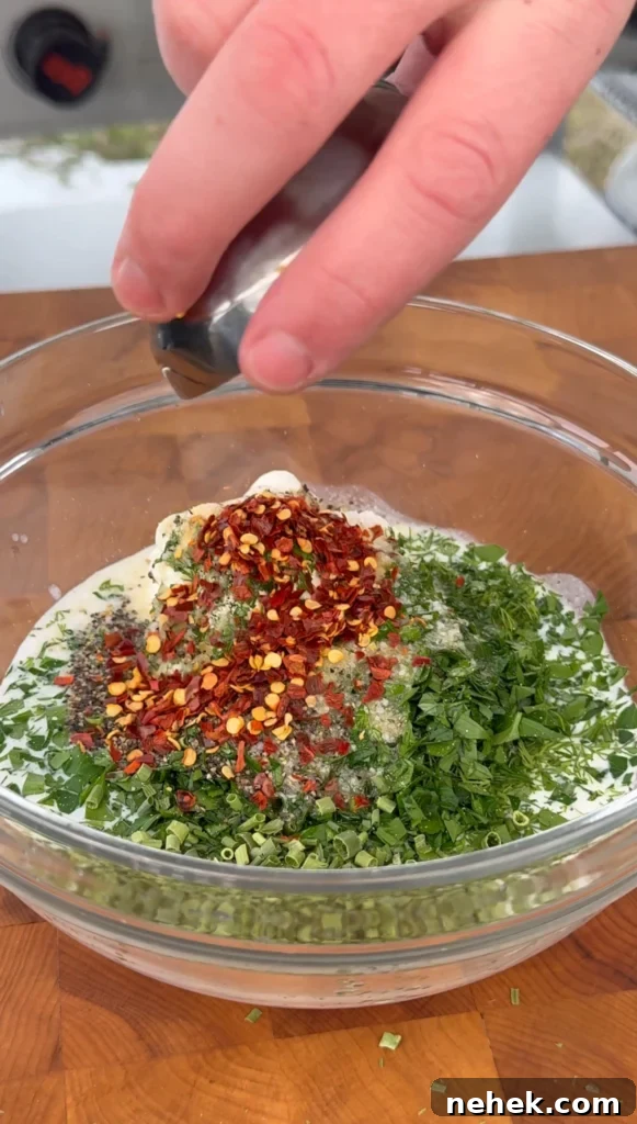 Homemade ranch dressing being whisked in a bowl with fresh herbs and buttermilk.