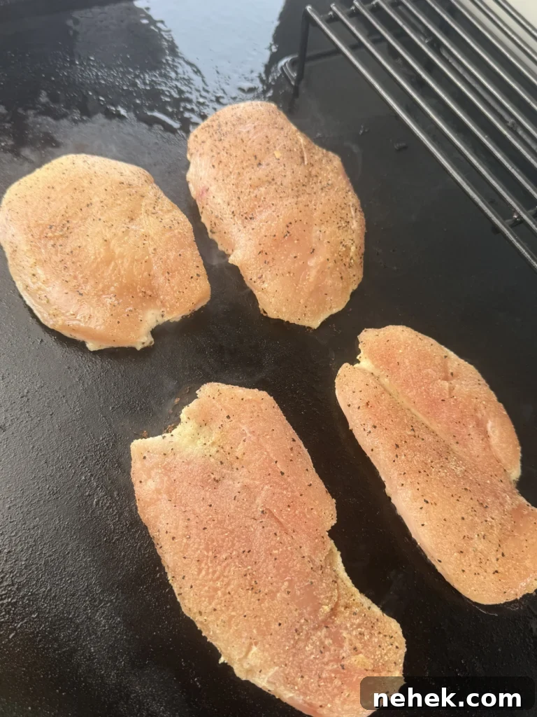 Raw boneless chicken breasts seasoned with garlic powder, smoked paprika, salt, and pepper.