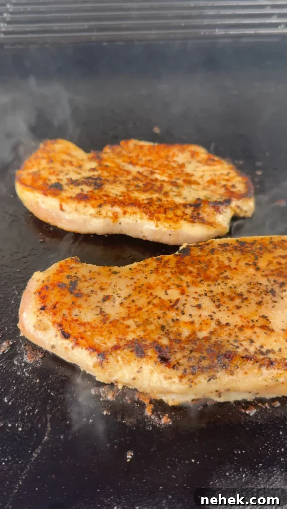 Grilled chicken breast topped on a griddle.