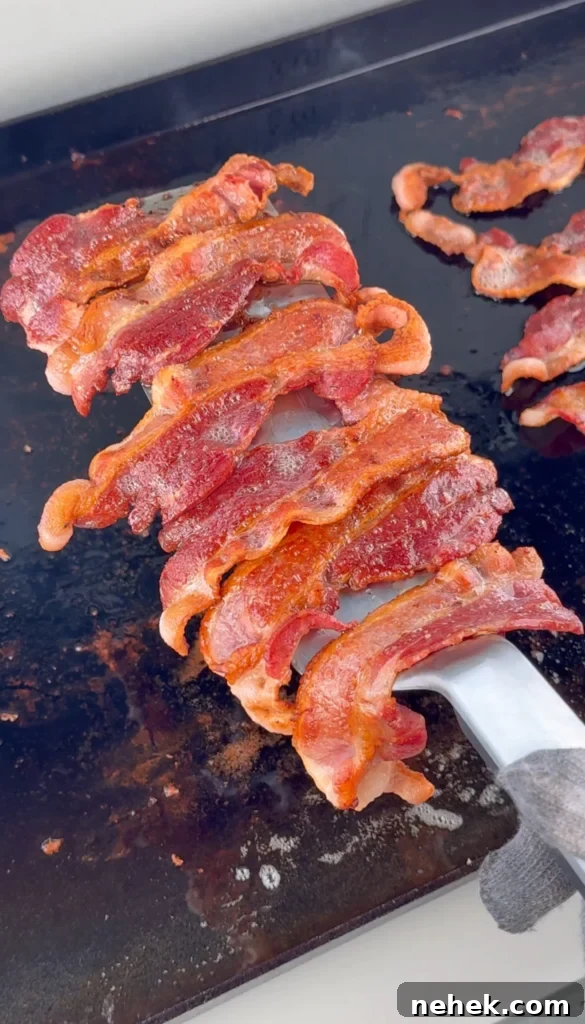 Strips of bacon sizzling in a cast-iron skillet until crispy.