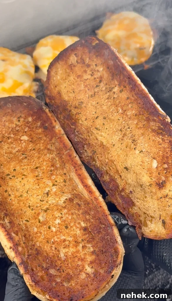 Toasted sandwich rolls on a griddle, golden brown and ready for assembling.