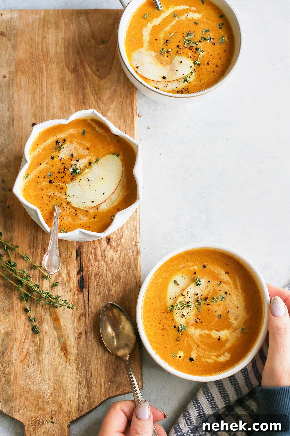 woman picking up a bowl of butternut squash soup and apple