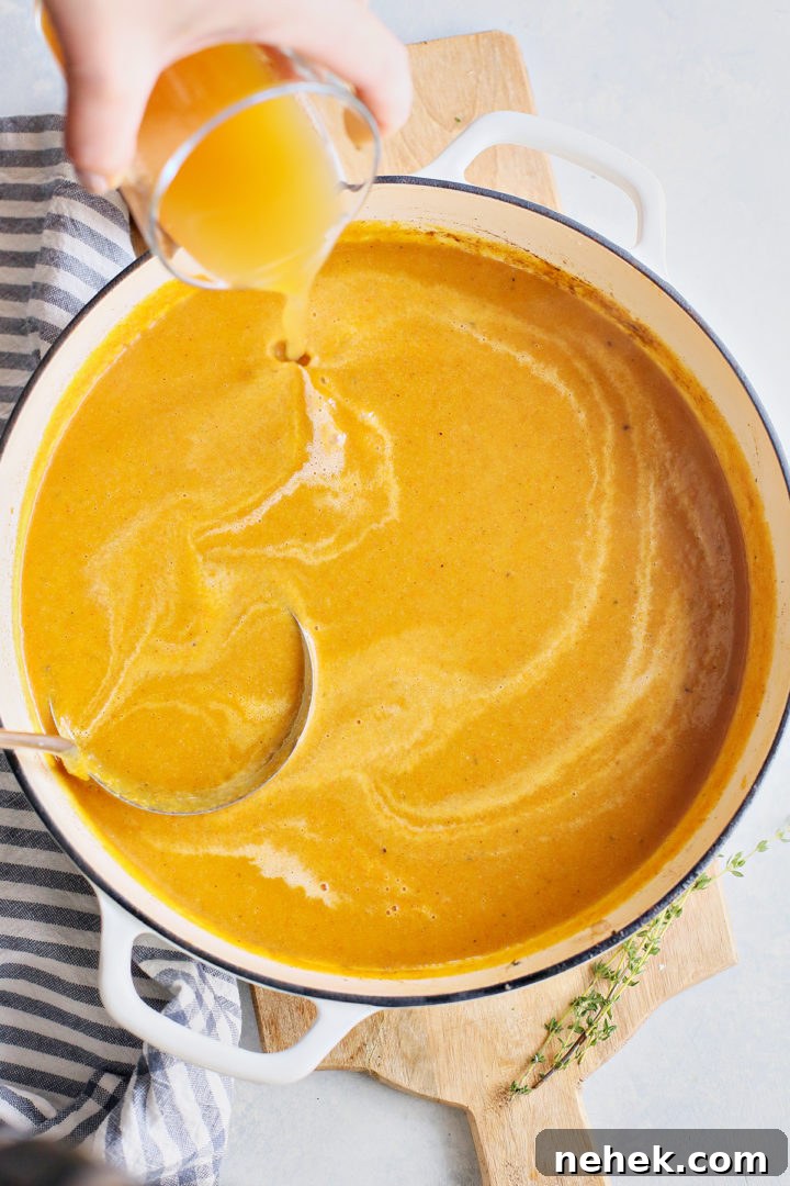 woman adding apple juice to spiced butternut soup