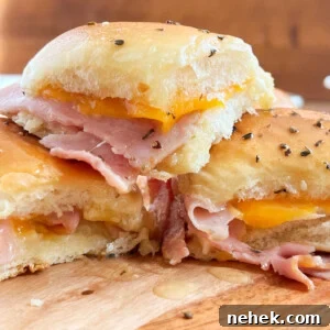 leftover ham sandwich made with spiral ham slices and cheddar cheese on buttery seasoned rolls on a serving board.