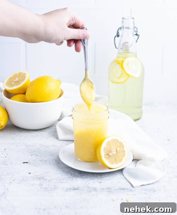 How to Fill Cupcakes Perfectly: 6 Methods for Delicious Centers 4 Lemon curd dripping from a silver spoon into a ½ pint jar of curd. Lemons in a bowl and lemonade in a decanter in the background.