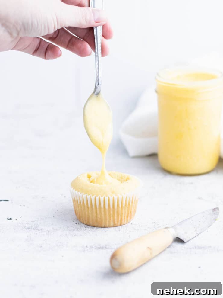 How to Fill Cupcakes Perfectly: 6 Methods for Delicious Centers 7 Cupcake with lemon curd dripping from a spoon into a whole in the center of the cupcake.