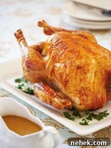 Classic Roast Turkey with Savory Homemade Gravy 3 An old-fashioned roast turkey on a white platter, with gravy in a boat beside it.
