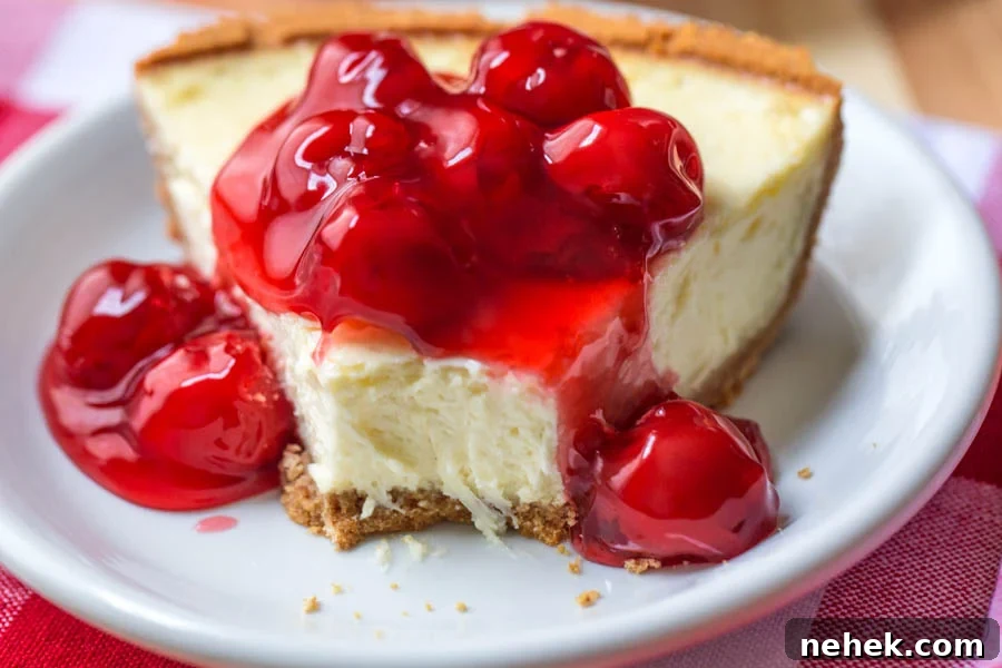 an easy homemade slice of cheesecake with cherry pie filling over the top on a white plate