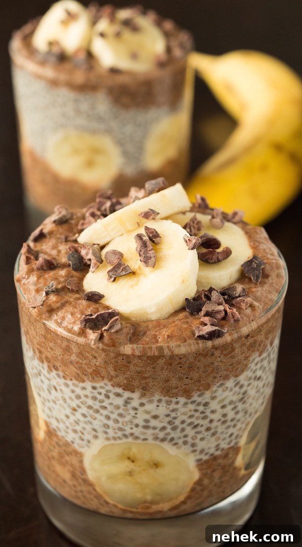 Banana Cacao Chia Seed Pudding Parfait Recipe for Breakfast 4 In focus in the foreground is a glass filled with layered chocolate and banana chia pudding with fresh banana slices and cacao nibs on top.