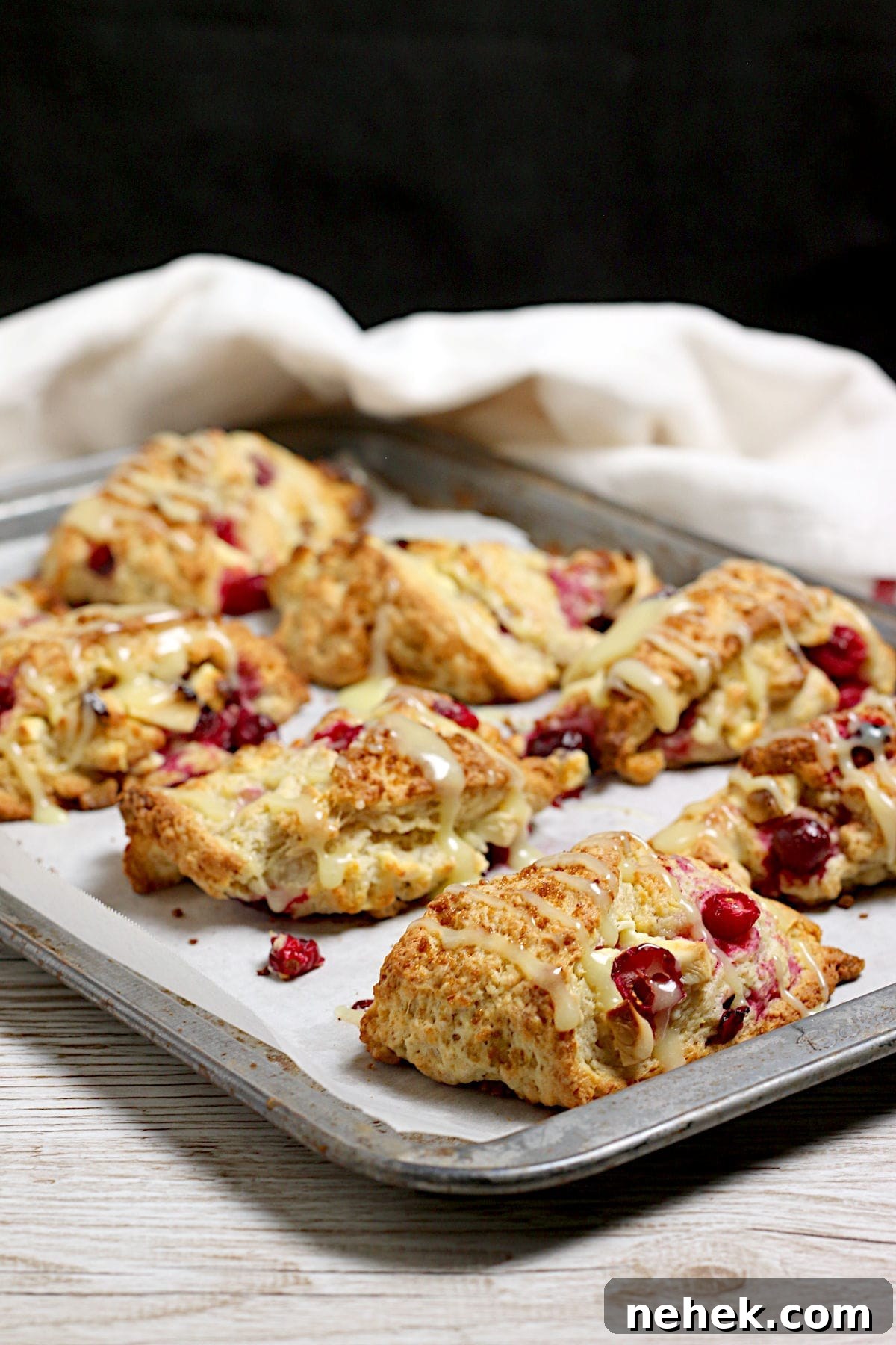 Cranberry Orange Scones with White Chocolate Drizzle 2 Cranberry Orange Scones with White Chocolate on a baking sheet.