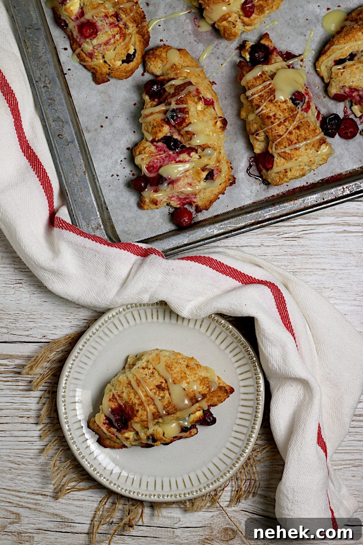 Cranberry Orange Scones with White Chocolate Drizzle 3 An overhead photo of a Cranberry Orange Scone with White Chocolate on a small white plate.