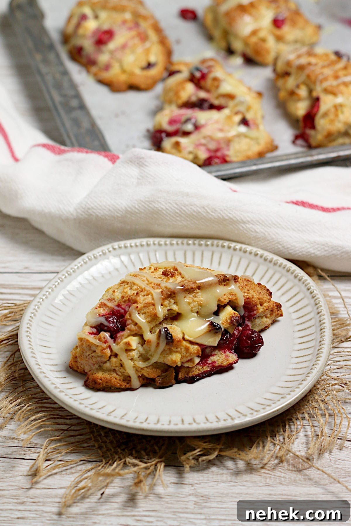 Cranberry Orange Scones with White Chocolate Drizzle 4 A Cranberry Orange Scone with White Chocolate on a small white plate.