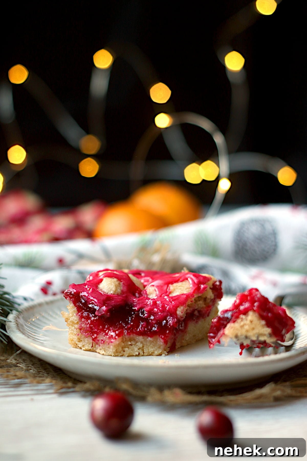 Cranberry Orange Scones with White Chocolate Drizzle 7 Closeup photo of a piece of cranberry pie bar on a small white plate.