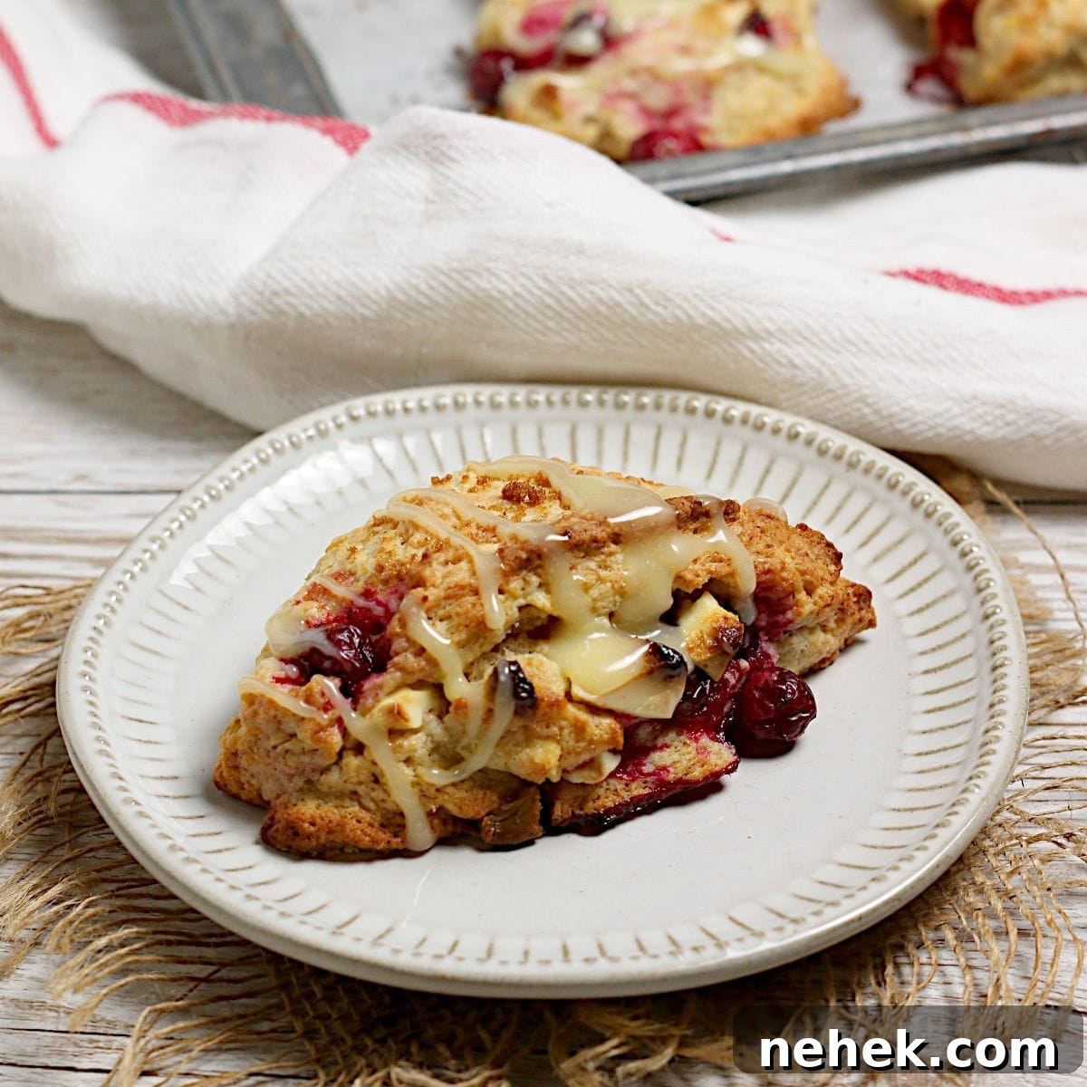 Cranberry Orange Scones with White Chocolate Drizzle 9 A Cranberry Orange Scone with White Chocolate on a small white plate.