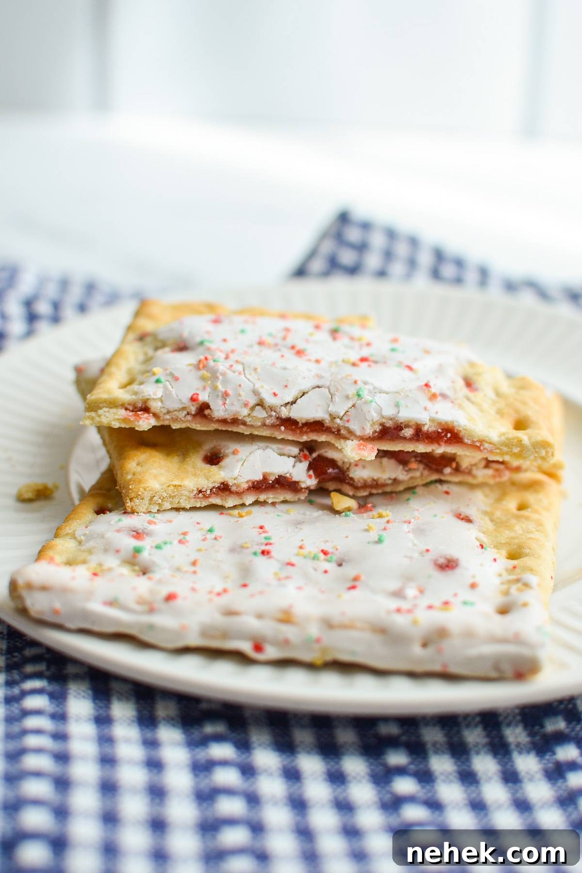 A pop tart, broken in two, resting on top of another pop tart on a plate.