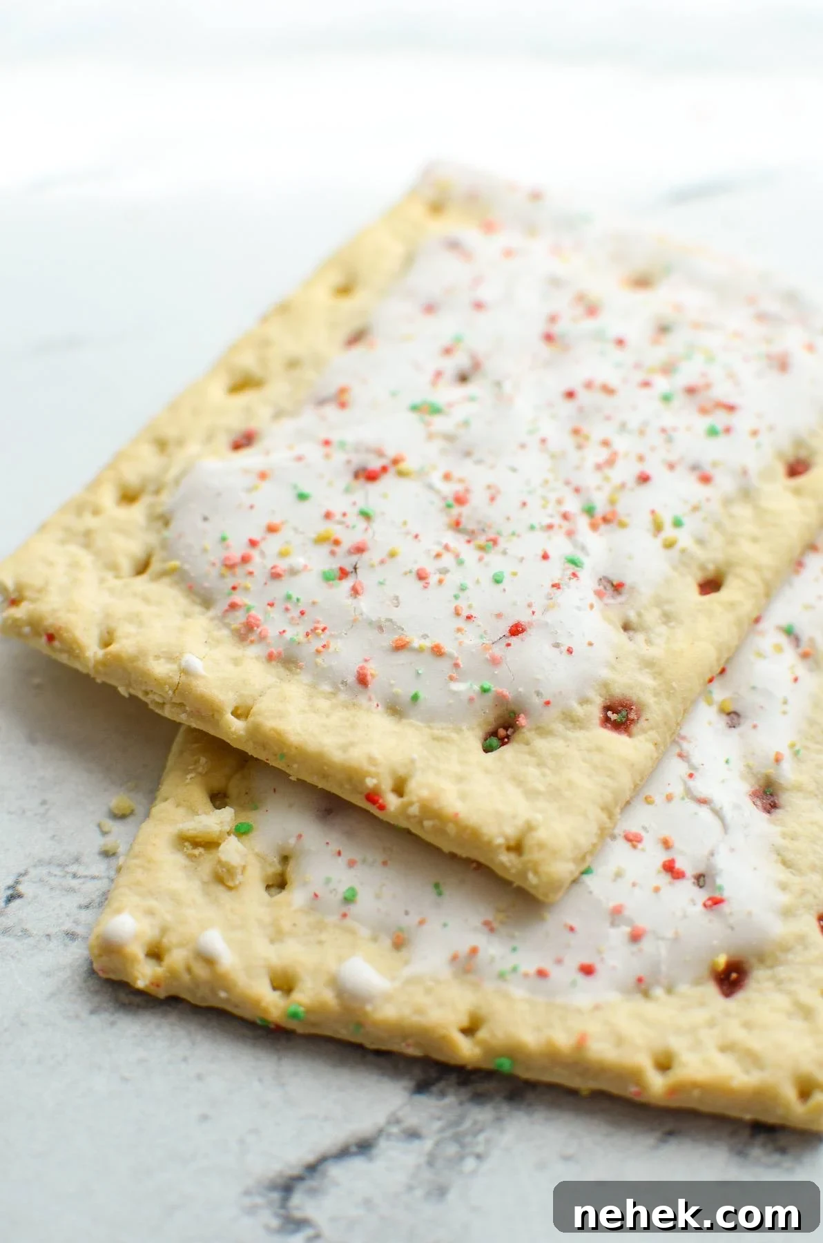 Two pop tarts laying on a marble counter.