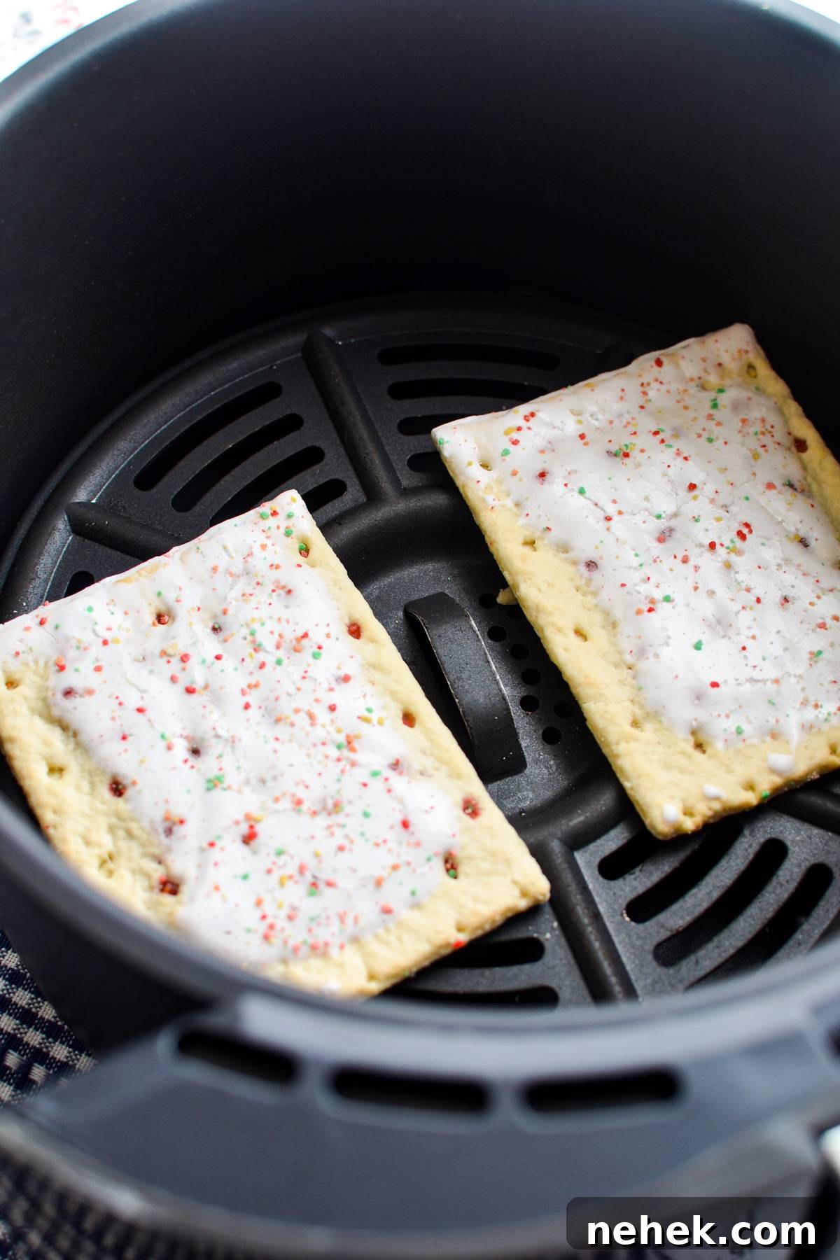 Adding pop tarts to the basket of an air fryer.