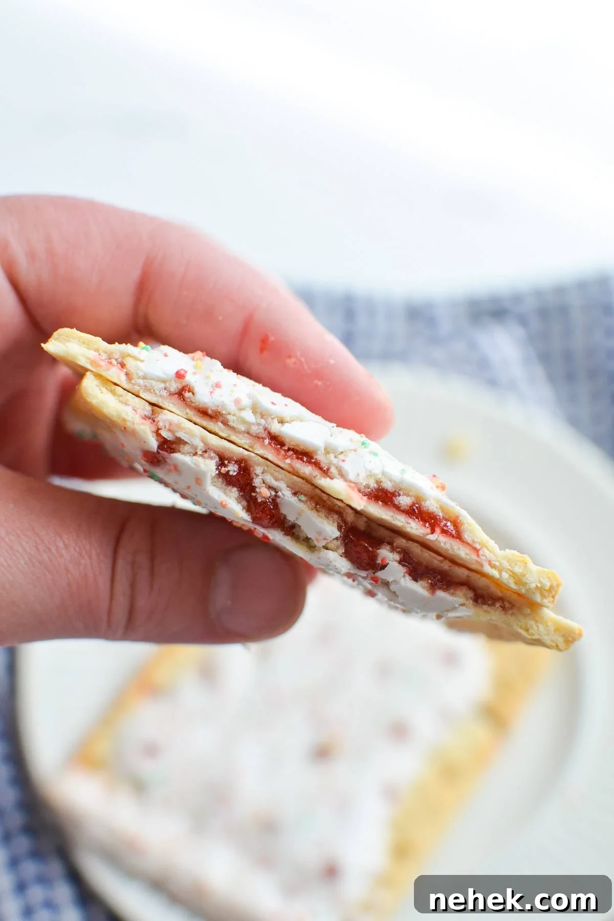 A hand holding pop tarts with a strawberry filling.