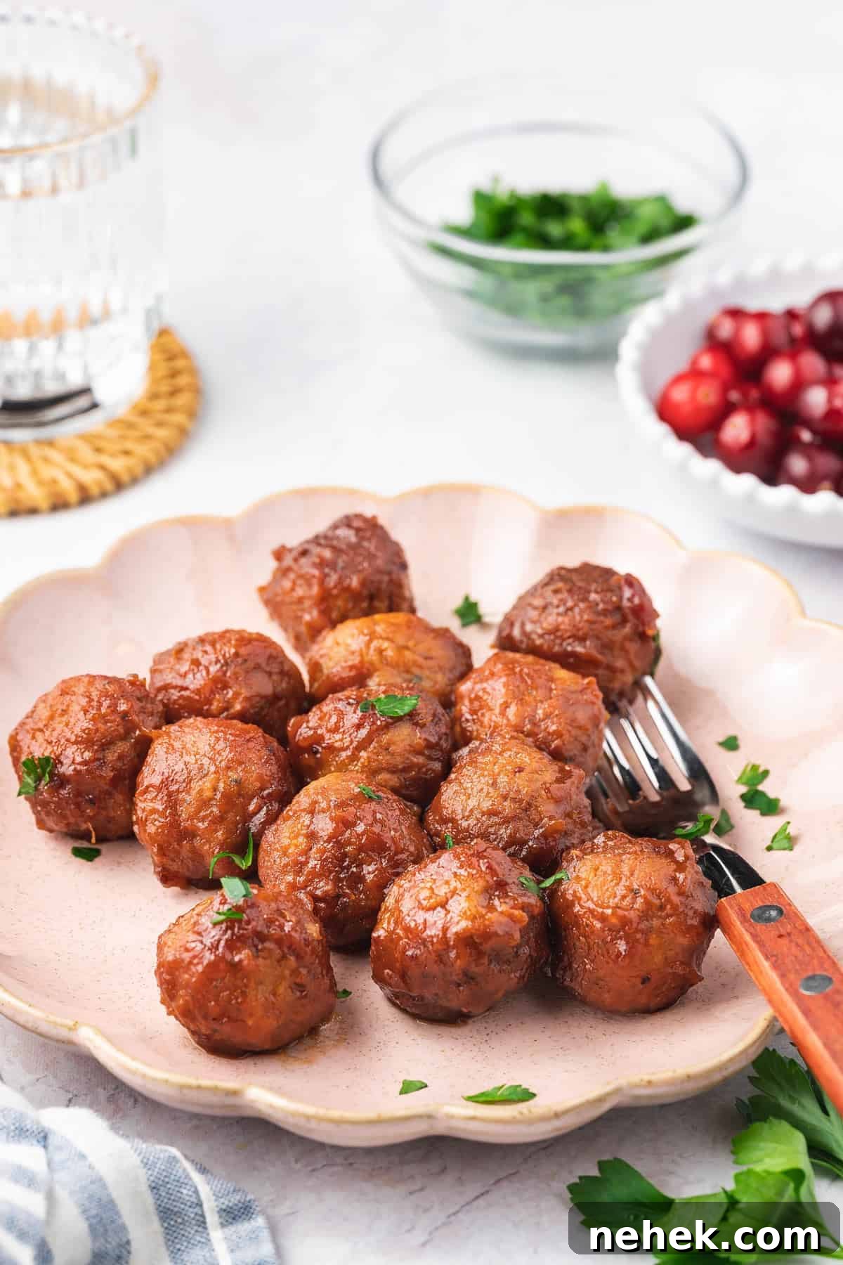 Angled view of a pink scalloped plate with slow cooker cranberry meatballs.